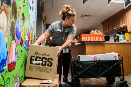 An ASYMCA staff member unloads boxes of food in their food pantry